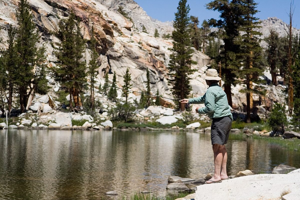 Angler casting at a backcountry mountain lake reached on foot