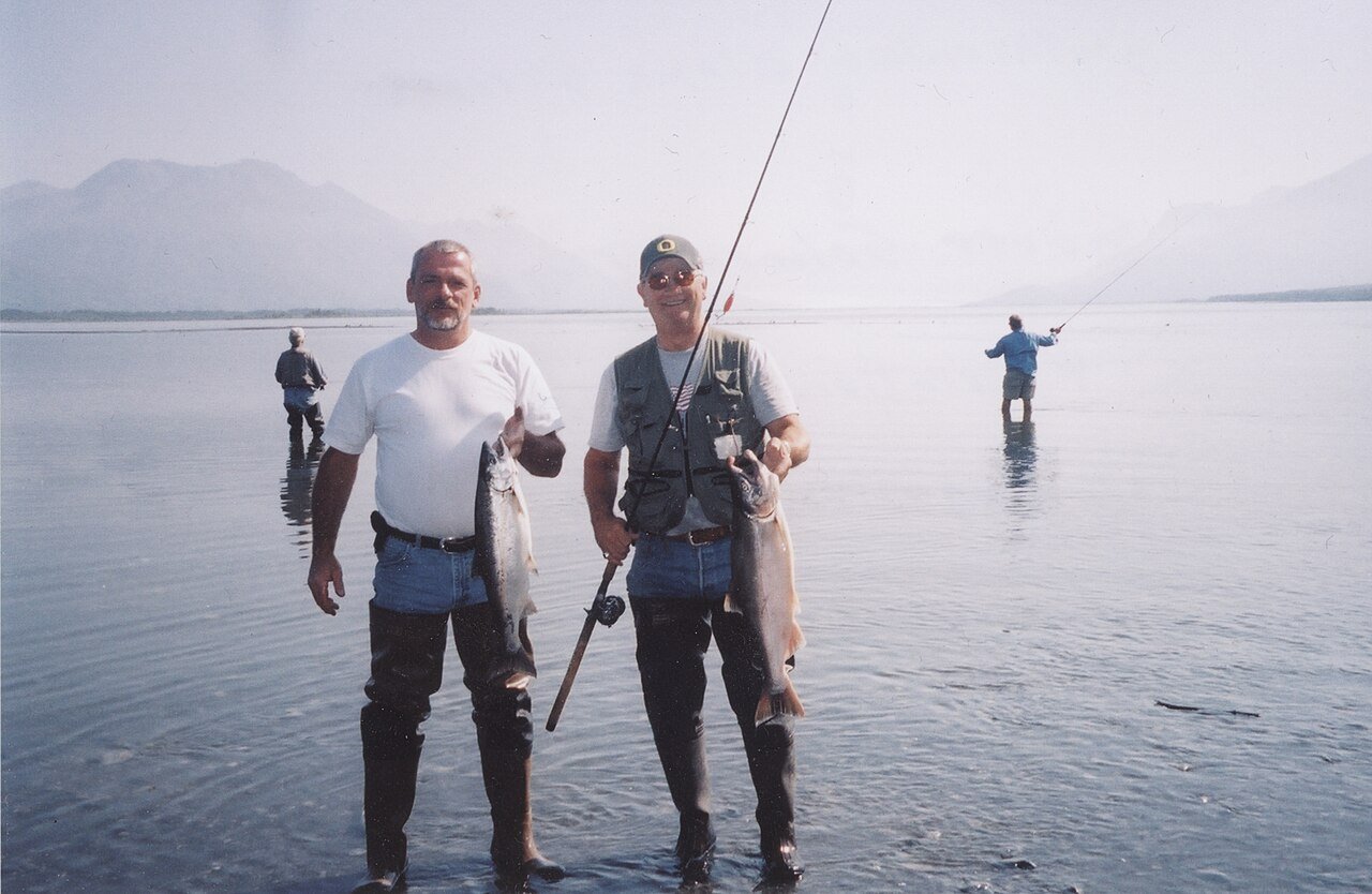 Two anglers in waders holding silver (coho) salmon in Alaska