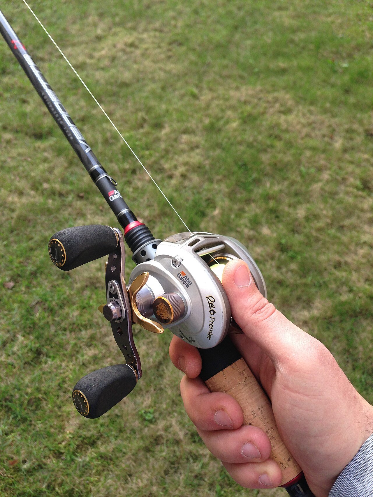 Hand holding a low-profile baitcasting reel on a casting rod