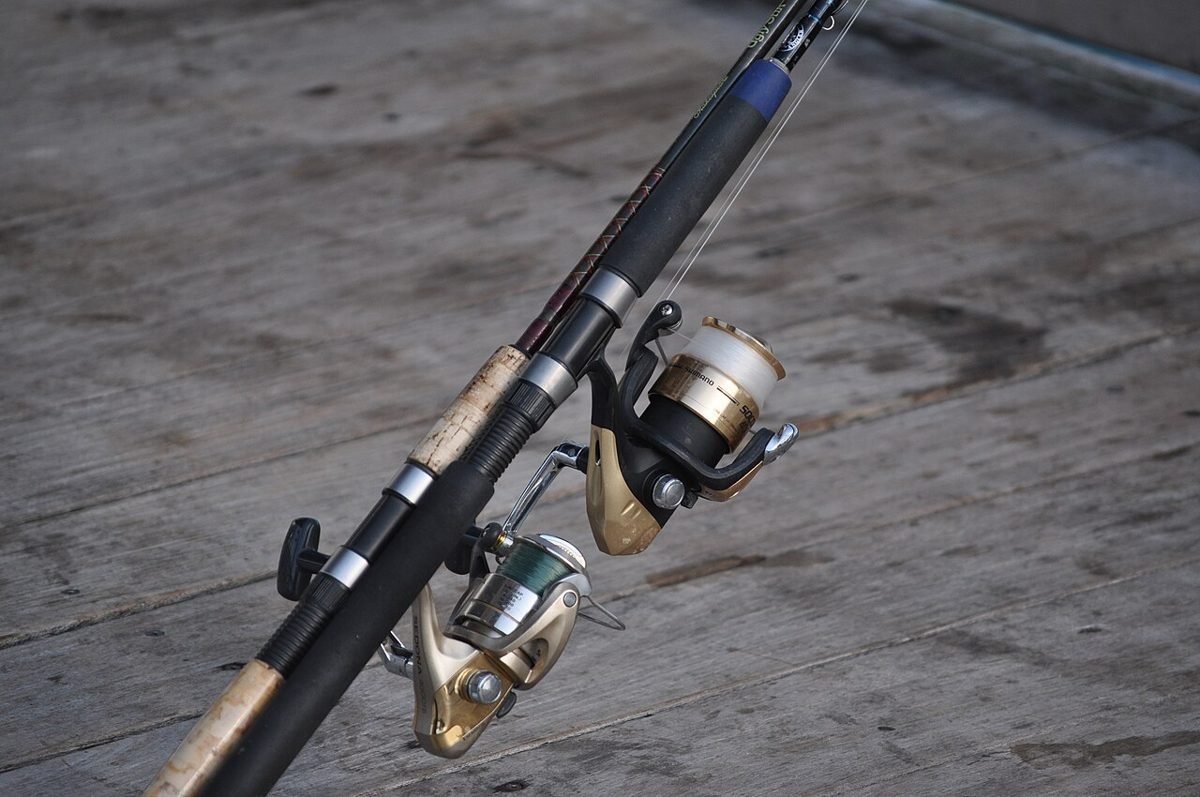 Two spinning rods and reels resting on a fishing pier